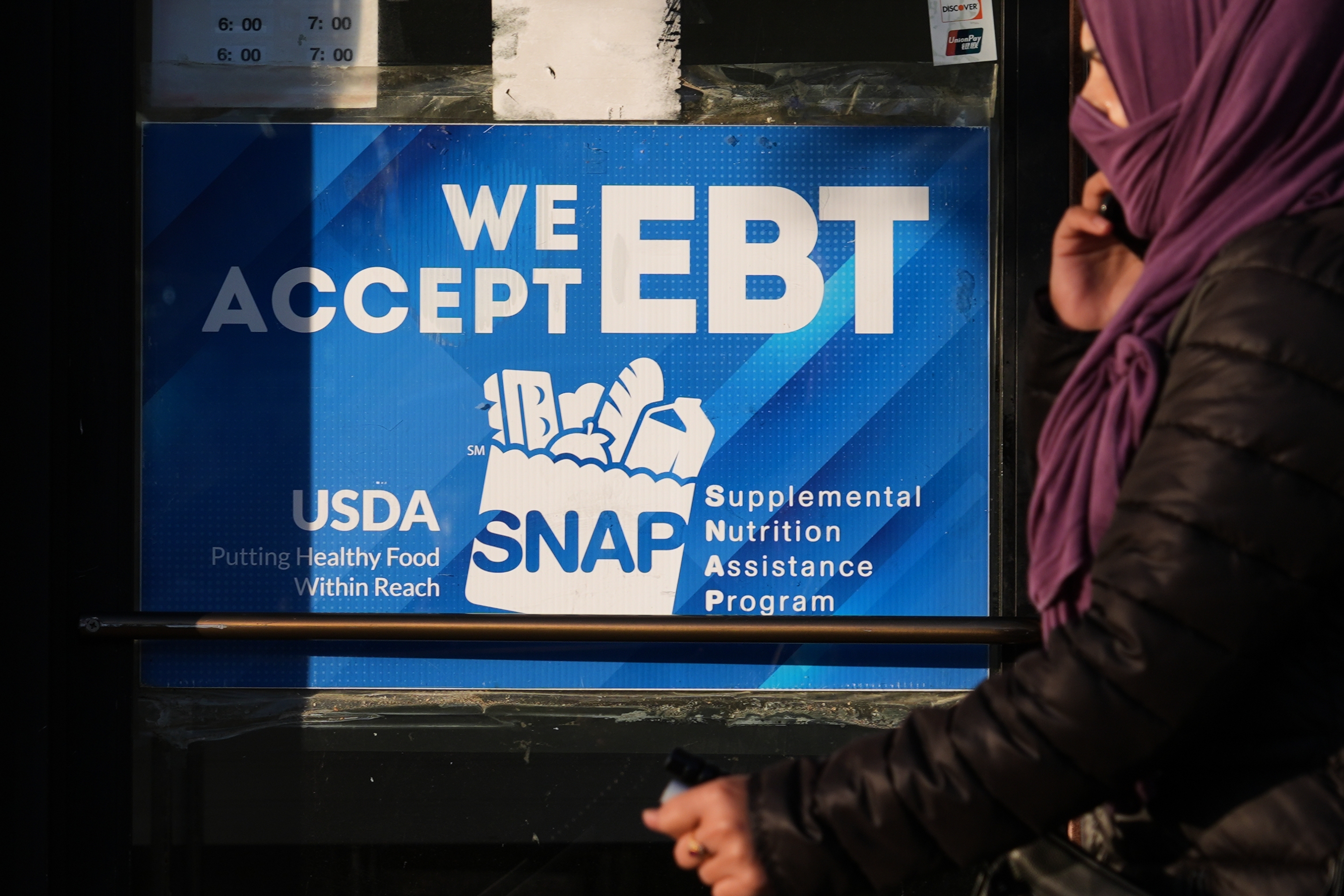 A SNAP EBT information sign is displayed at a bakery as a woman walks past in Chicago, Nov. 2.